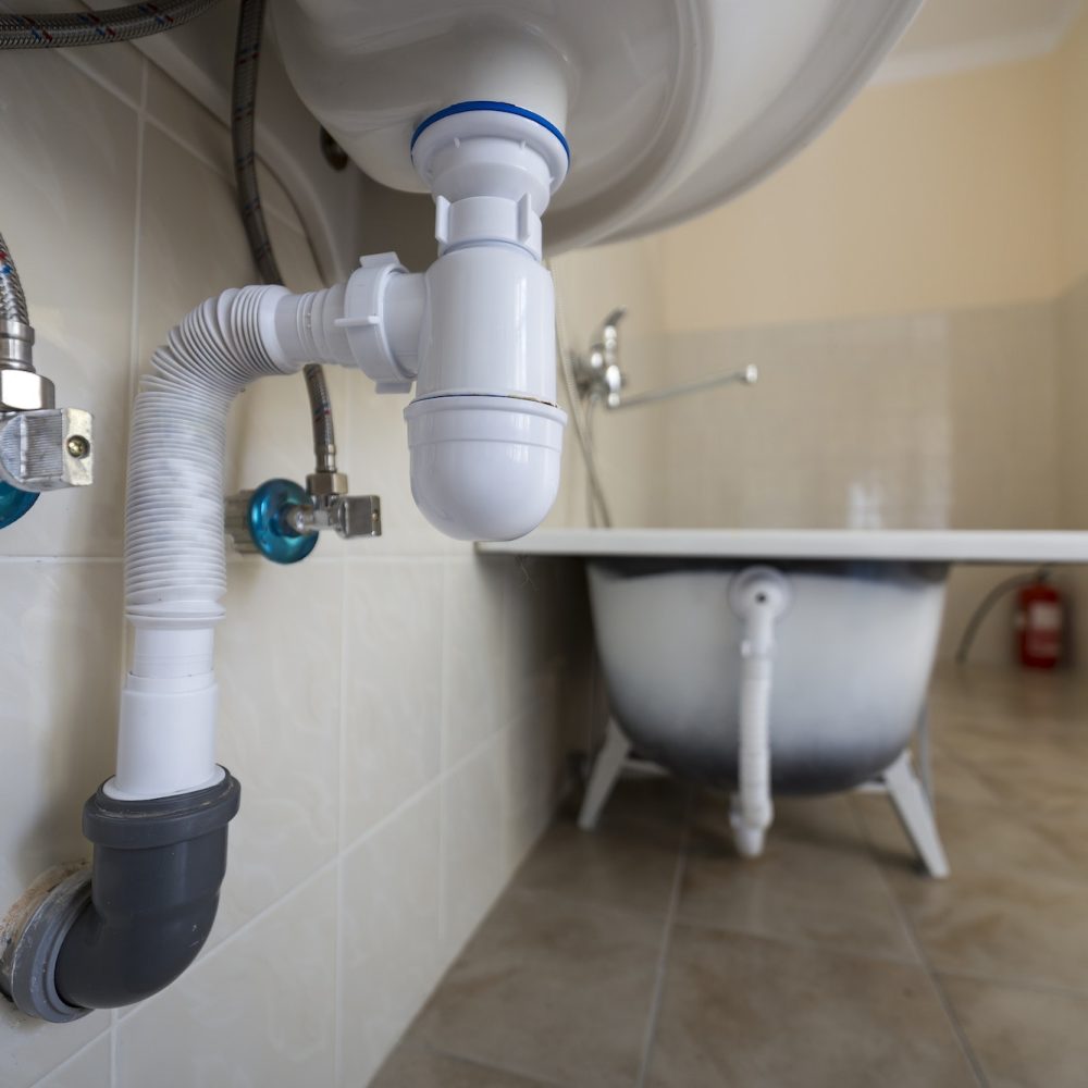 Bottom view of new white washbasin sink connected to sewer