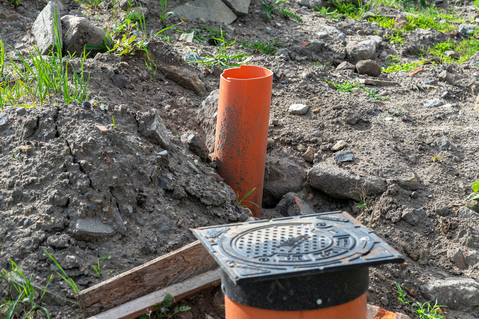 Sewage system with a closed cast iron manhole and visible plastic pipes