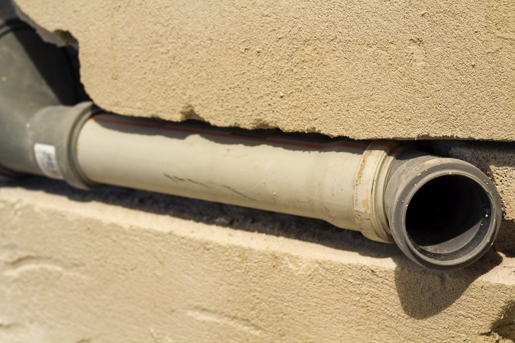 Gray sewer pipes being installed along a bathroom wall during renovation