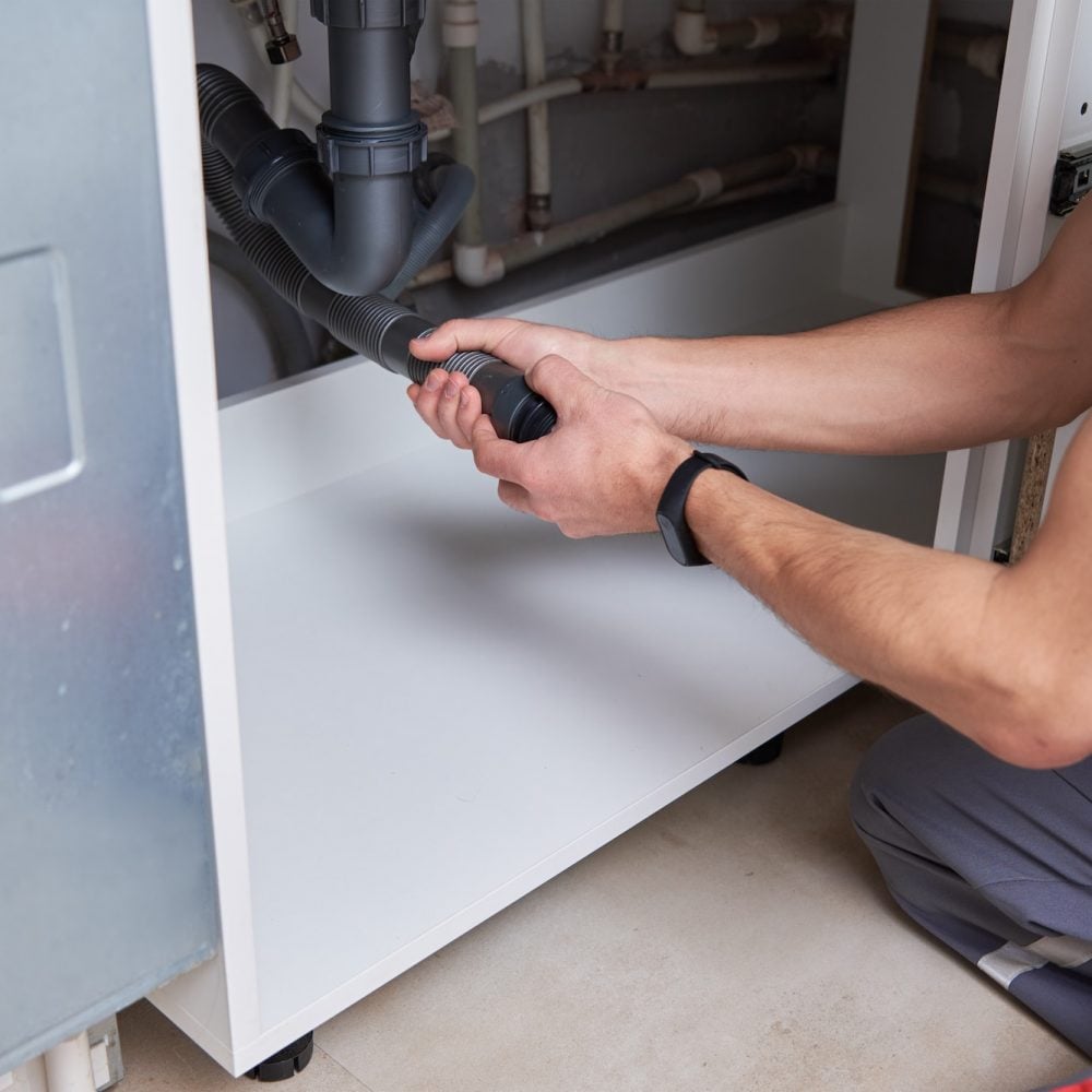 Male plumber repair sink pipe in kitchen