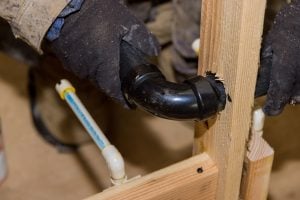 Plumbing building contractor installing plastic drain pipe in the elbow for sink drain for a custom
