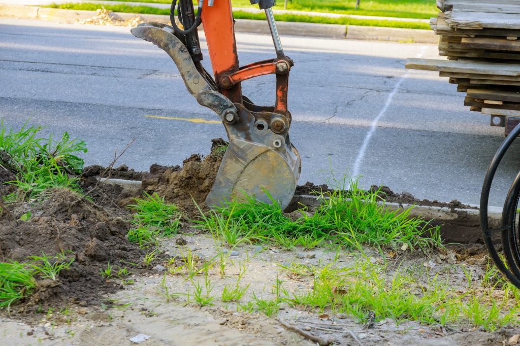 Urban municipal tractor with ladle is dig the sewer